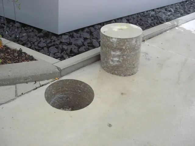 Clean diamond core hole drilled through a concrete slab, with the removed concrete core beside it