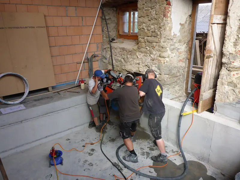 Core drilling crew operating a stand-mounted diamond core drill on a concrete job site